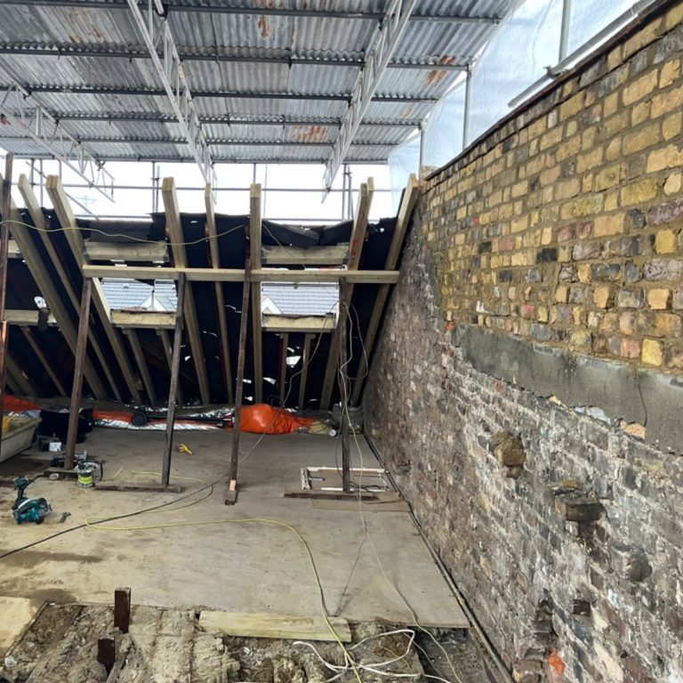 Loft extension party wall Construction site showing exposed brick wall and scaffolding, building a loft extension and raising the parapet wall.